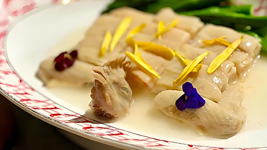 江南百花鸡成菜:鸡件呈日字形摆盘,鸡头鸡尾配对复原整鸡形态,撒上夜来香花瓣