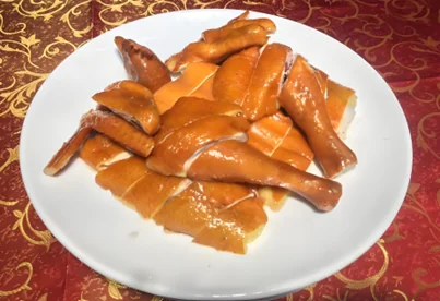 玫瑰露豉油鸡成品：斩件摆盘，鸡皮枣红透亮油润，白盘衬底，皮肉之间一层胶质