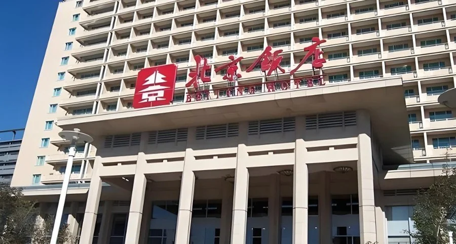 北京饭店:米色大楼正门上红色「北京饭店」四字招牌与方形「京」字徽标,楼上是层层叠叠的客房阳台